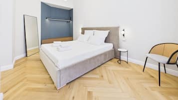 Un dormitorio moderno con una cama grande, una mesita de noche, una silla y un espejo.