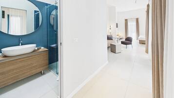 A modern bathroom with a large oval mirror, a white sink, and a wooden vanity.