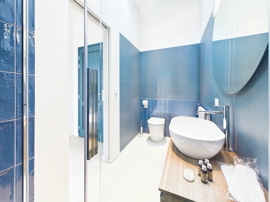 Une salle de bain moderne avec un grand lavabo blanc, des toilettes et une cabine de douche en verre.