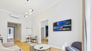 Una sala de estar moderna con un sofá, una mesa redonda de centro y un televisor montado en la pared.