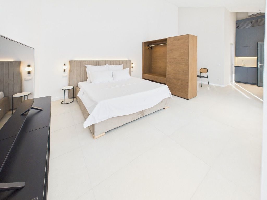 Et moderne hotelværelse med en stor seng, et træskab, et lille bord og en stol.
