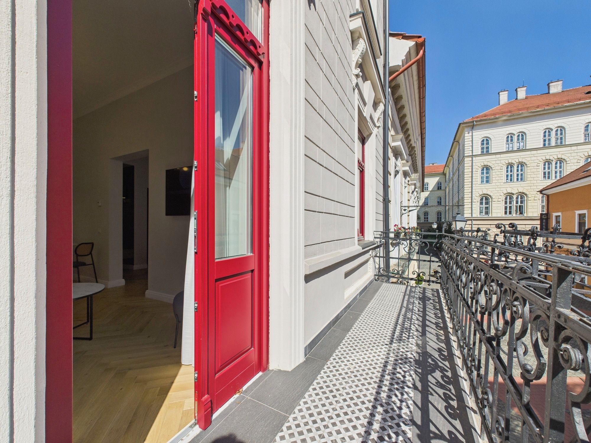 A red door leading to a room with a white wall and a small table.