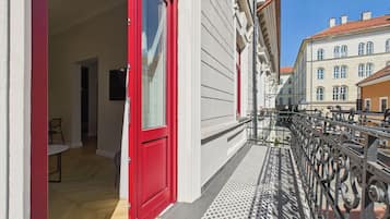 A red door leading to a room with a white wall and a small table.