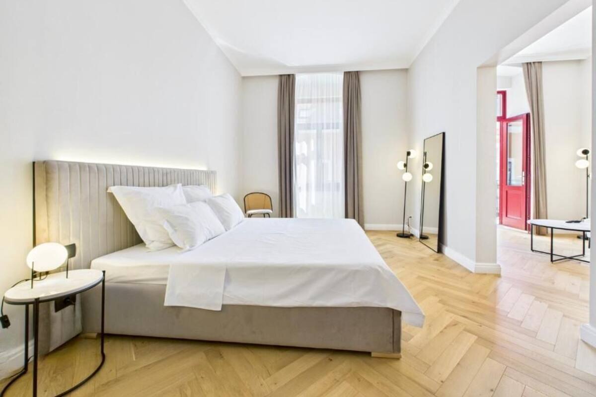 A modern hotel room with a large bed, bedside table, and a mirror.