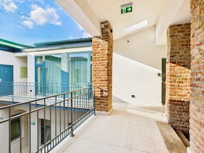 A modern building with a glass facade, a brick column, and a metal railing. - Griselini Boutique Suites (Timișoara)