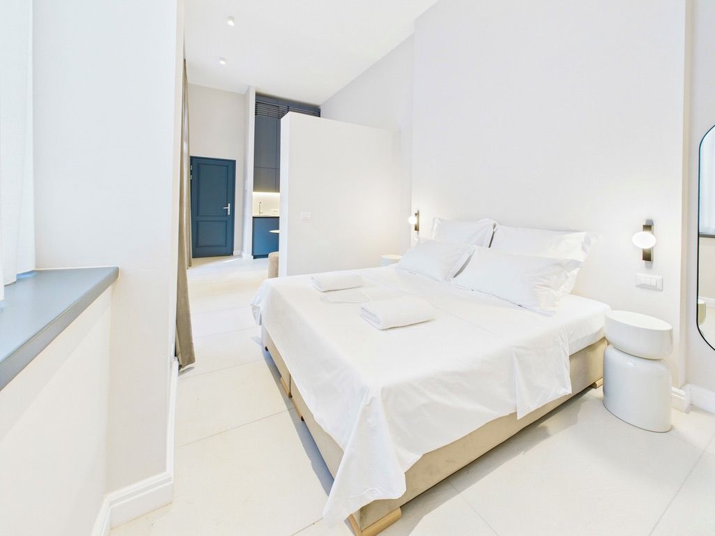 A modern bedroom with a large bed, bedside tables, and a bathroom with a toilet and sink.