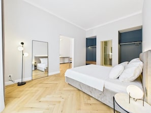A modern bedroom with a large bed, a bedside table, a mirror, and a floor lamp. - Griselini Boutique Suites (Timișoara)
