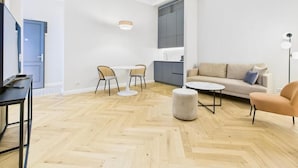 A modern living room with a sofa, chairs, a coffee table, and a TV. - Griselini Boutique Suites (Timișoara)