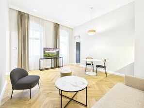 A modern living room with a sofa, a round table, and a television. - Griselini Boutique Suites (Timișoara)