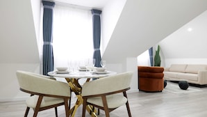 A dining area with a round table, chairs, and a sofa in a modern interior. - The Wembley Crown Heights 1 Bed Flat  (Wembley)