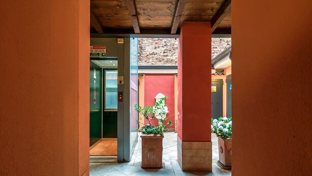 A corridor with a wooden ceiling, a red wall, and a potted plant. - Laura's Home (Brescia)