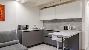 A modern kitchen with white cabinets, a marble backsplash, a built-in oven, and a bar stool. - Laura's Home (Brescia)