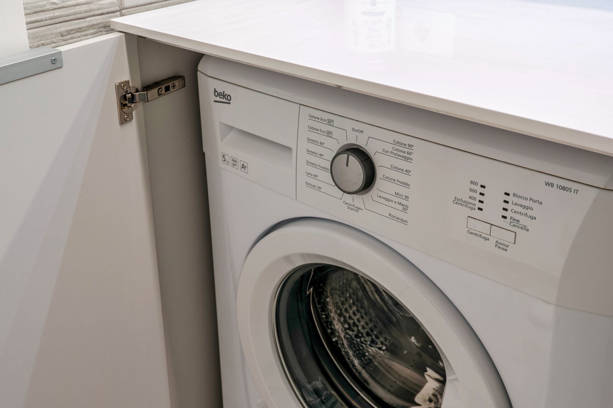 A front view of a white washing machine with a control panel, a door, and a visible door latch.