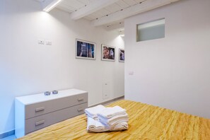 A hotel room with a wooden bed, a white dresser, and three framed pictures on the wall. - Laura's Home (Brescia)