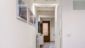 A hallway with framed pictures on the wall, a radiator, and a door leading to another room. - Laura's Home (Brescia)