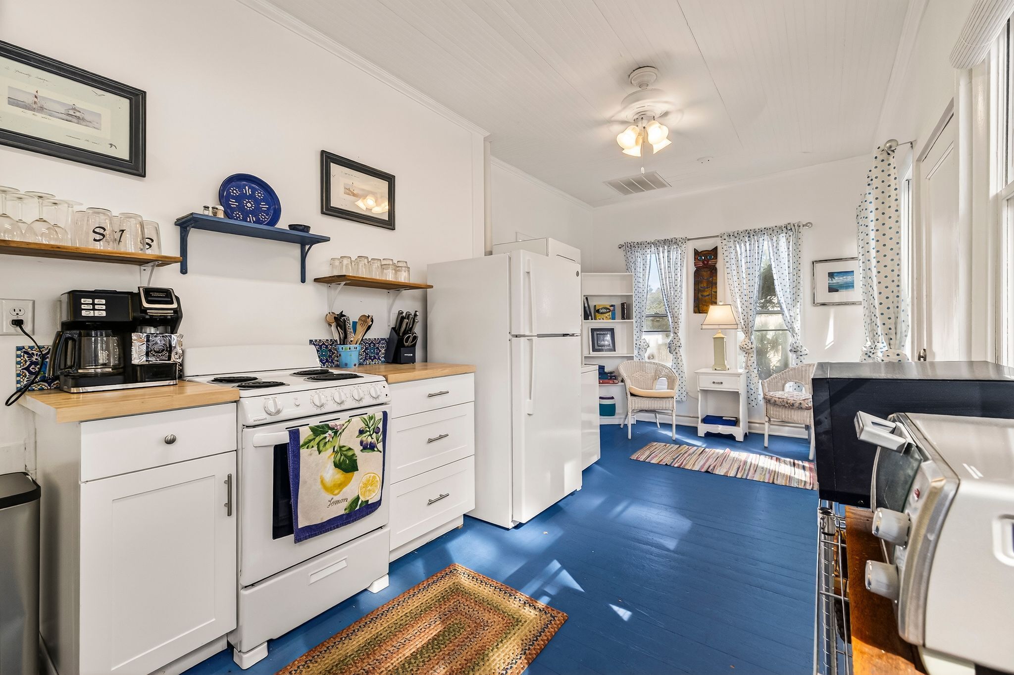 A compact kitchen with white appliances, a coffee maker, and a stove.