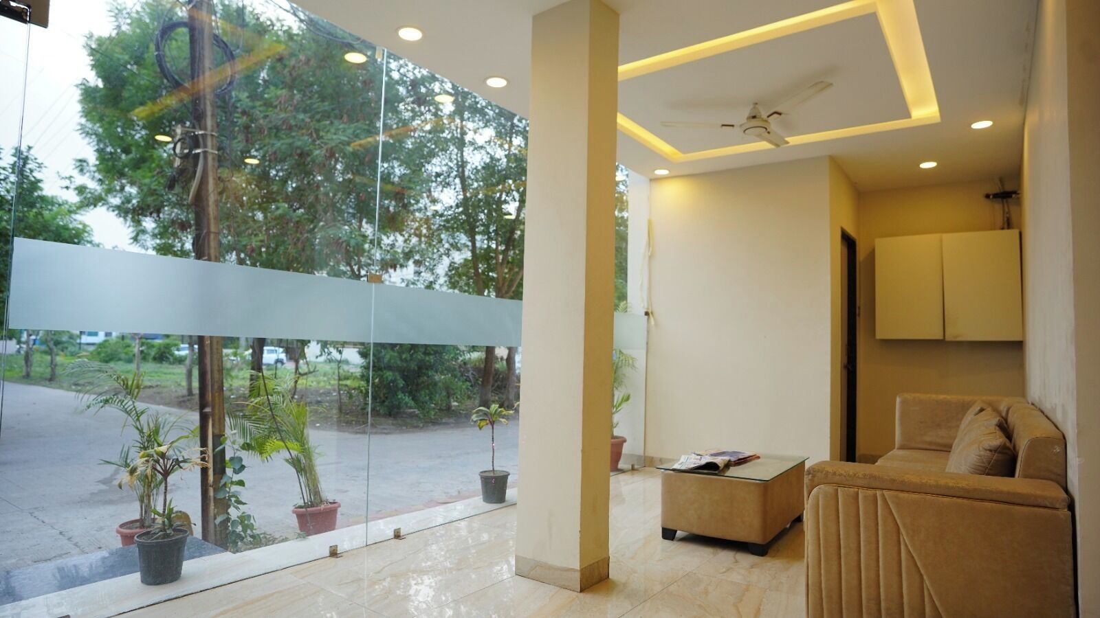 A modern interior with a glass partition, a sofa, a small table, and a ceiling fan.