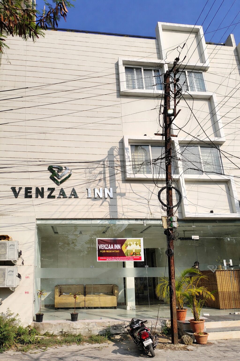 A building with a sign reading 'VENZAA INN' and a banner advertising the inn. There are potted plants and a motorcycle outside.