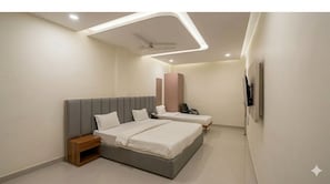 Un dormitorio moderno con una cama grande, una cama más pequeña, una mesita de noche, un ventilador de techo e iluminación empotrada.