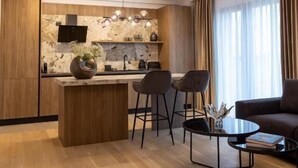 A modern kitchen with a marble backsplash, wooden cabinets, and a central island with bar stools. - MaisonA (Timișoara)