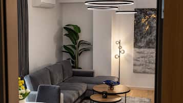 A modern living room with a grey sectional sofa, a floor lamp, and a potted plant.