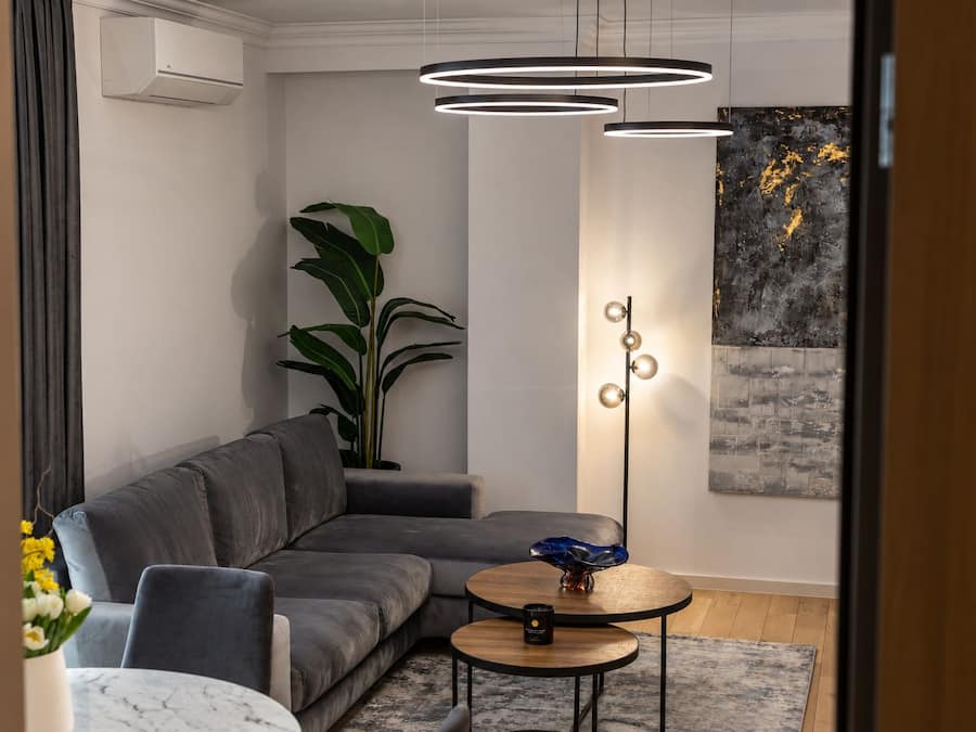 A modern living room with a grey sectional sofa, a floor lamp, and a potted plant.