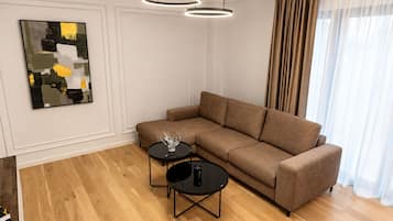 Una sala de estar moderna con un sofá modular, dos mesas redondas negras y un cuadro abstracto contemporáneo en la pared.