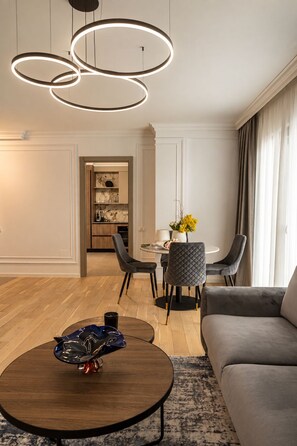 A modern living room with a round coffee table, a grey sofa, and a dining area with a table and chairs. - MaisonA (Timișoara)