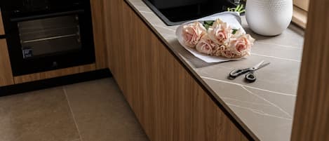 A kitchen with a built-in oven, a sink, and a countertop with a bouquet of flowers and a pair of scissors.
