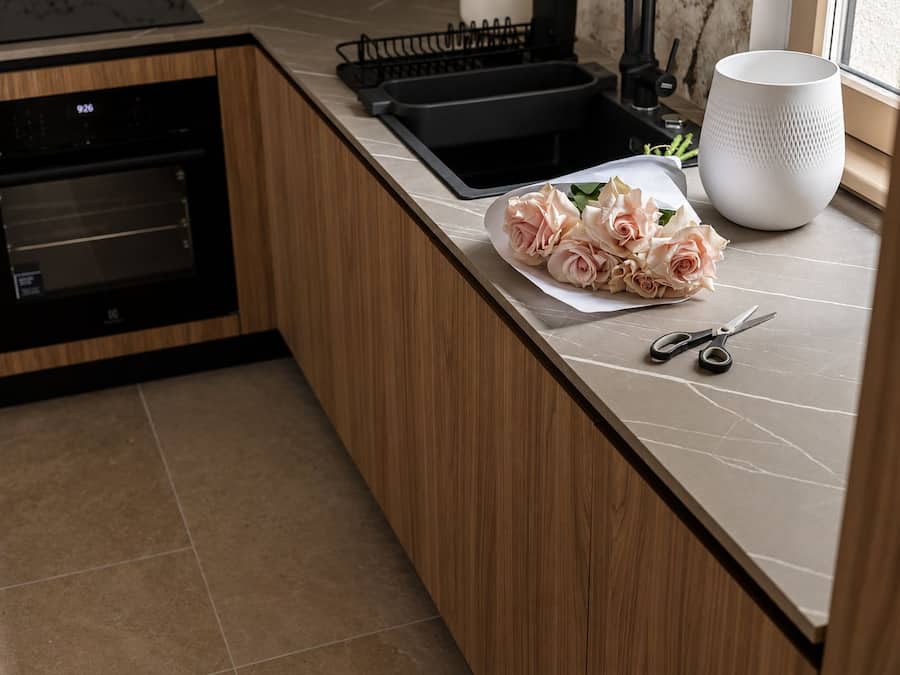 A kitchen with a built-in oven, a sink, and a countertop with a bouquet of flowers and a pair of scissors.