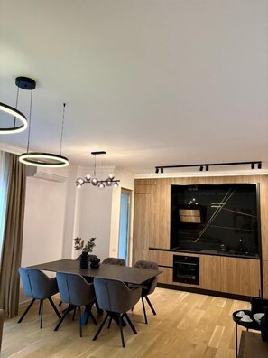Un espace repas moderne avec une table rectangulaire, quatre chaises et des luminaires suspendus.