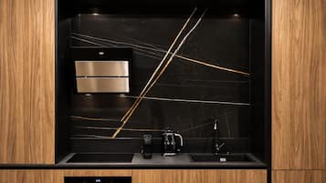 A modern kitchen with a built-in oven, a coffee maker, and a sink.