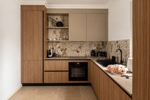 A modern kitchen with wooden cabinets, a marble backsplash, and a built-in oven. - MaisonA (Timișoara)