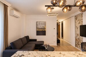 A modern living room with a sectional sofa, a marble coffee table, and a unique spherical light fixture. - MaisonA (Timișoara)
