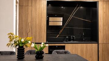 A modern kitchen with a built-in oven, a coffee maker, and a black backsplash.