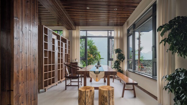 A wooden interior with a large table, chairs, and a bookshelf. - Zhangjiajie Stone Forest Retreat (Zhangjiajie)