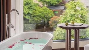 A bathroom with a bathtub, a window, and a small wooden table with two apples. - Zhangjiajie Stone Forest Retreat (Zhangjiajie)