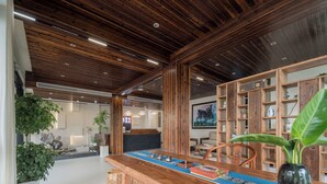 A wooden reception desk, a large plant, and a wooden bookshelf in a lobby area. - Zhangjiajie Stone Forest Retreat (Zhangjiajie)