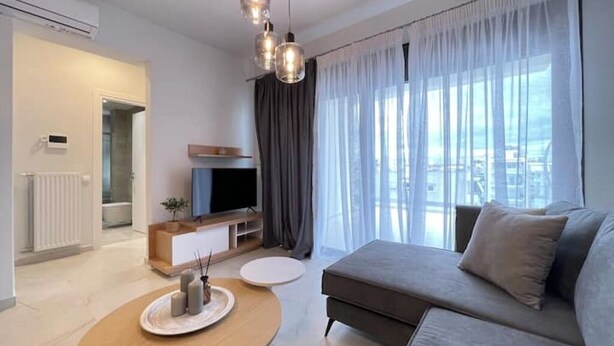Een moderne woonkamer met een bank, televisie en een eethoek met een tafel en kaarsen.