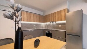 Een moderne keuken met houten kastjes, een roestvrijstalen koelkast en een eettafel met een vaas en een zwart voorwerp.