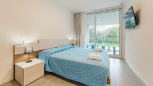 A bedroom with a bed, a nightstand, a TV, and a large window. - Le Residenze Di Zelo - Private Parking (Mestre)