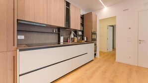 A modern kitchen with wooden cabinets, a countertop, and a built-in oven. - Le Residenze Di Zelo - Private Parking (Mestre)