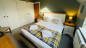 Una habitación de hotel con cama, mesita de noche, armario y escritorio.