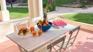 A table with croissants, a fruit bowl, a glass of orange juice, and a book titled 'PORTA BELLITA'. - Sunny Village Vilamoura (Loulé)