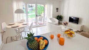 A modern living room with a dining area, a TV, and a balcony with outdoor furniture. - Sunny Village Vilamoura (Loulé)