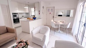 A modern apartment with a kitchenette, a dining area, and a living room with a sofa and armchairs. - Sunny Village Vilamoura (Loulé)
