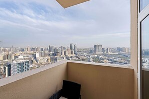 Ein Balkon mit Blick auf die Stadt, ein Stuhl und ein Fenster.