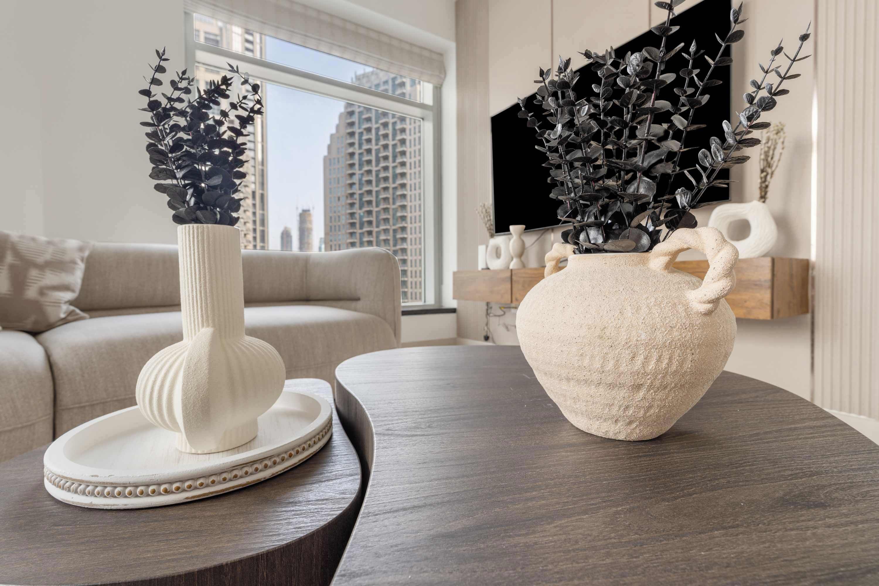 Un salon moderne avec un canapé, une table basse en bois foncé et deux vases ornés de plantes.