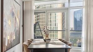 A dining area with a table, chairs, a vase with flowers, and a large abstract painting on the wall. - Luxury 2BR in Downtown Dubai, Near Burj Khalifa (Downtown)