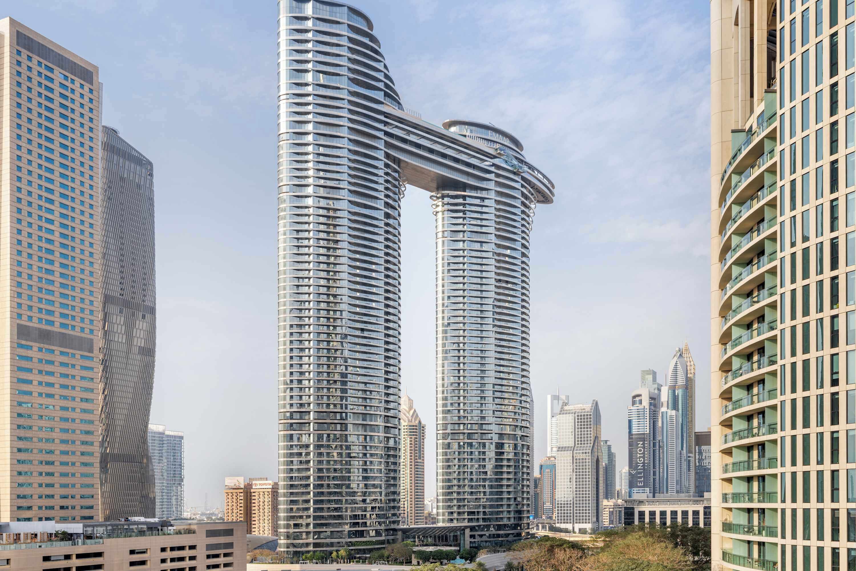 A modern high-rise building with a curved glass facade, surrounded by other tall buildings.